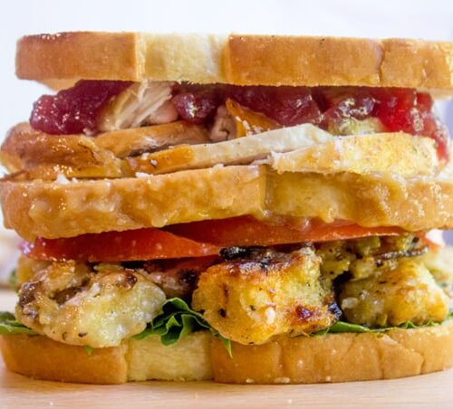 Thanksgiving leftovers sandwich stacked with turkey, stuffing, and cranberry.