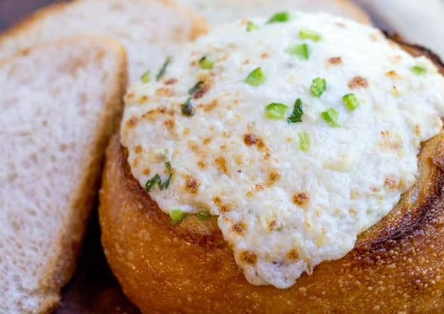 artichoke dip with scallions in bread bowl