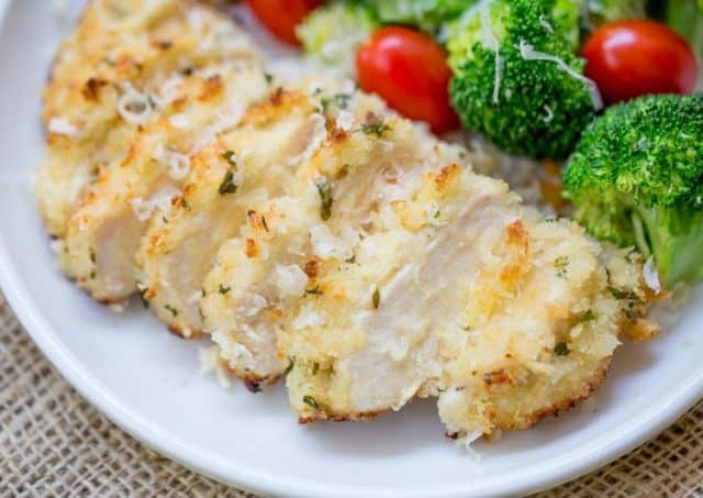 sliced lemon chicken with parmesan on plate with broccoli and tomatoes