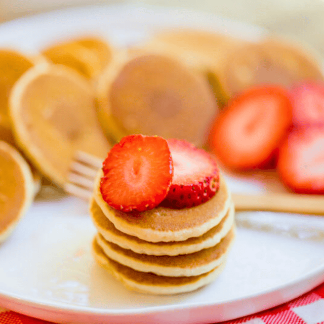 small circle hotcakes stacked on one another with strawberries