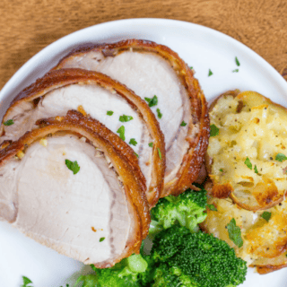Sliced meat on a plate with potatoes and broccoli