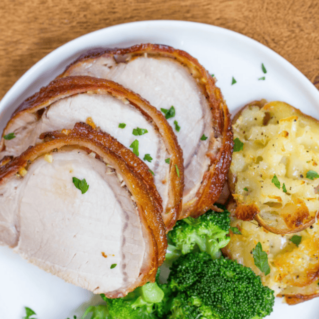 Sliced meat on a plate with potatoes and broccoli