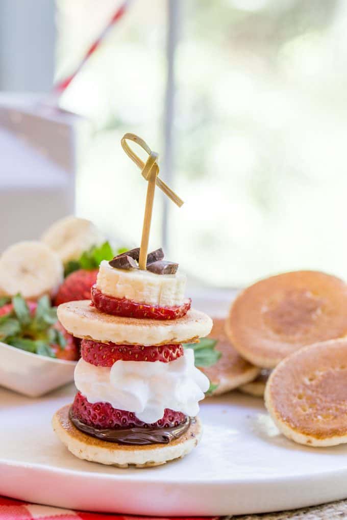 Banana Split Pancake Bites are an easy brunch dish for a party or for your little ones with homemade silver dollar pancakes, Nutella, bananas, strawberries, whipped cream and chocolate chips.