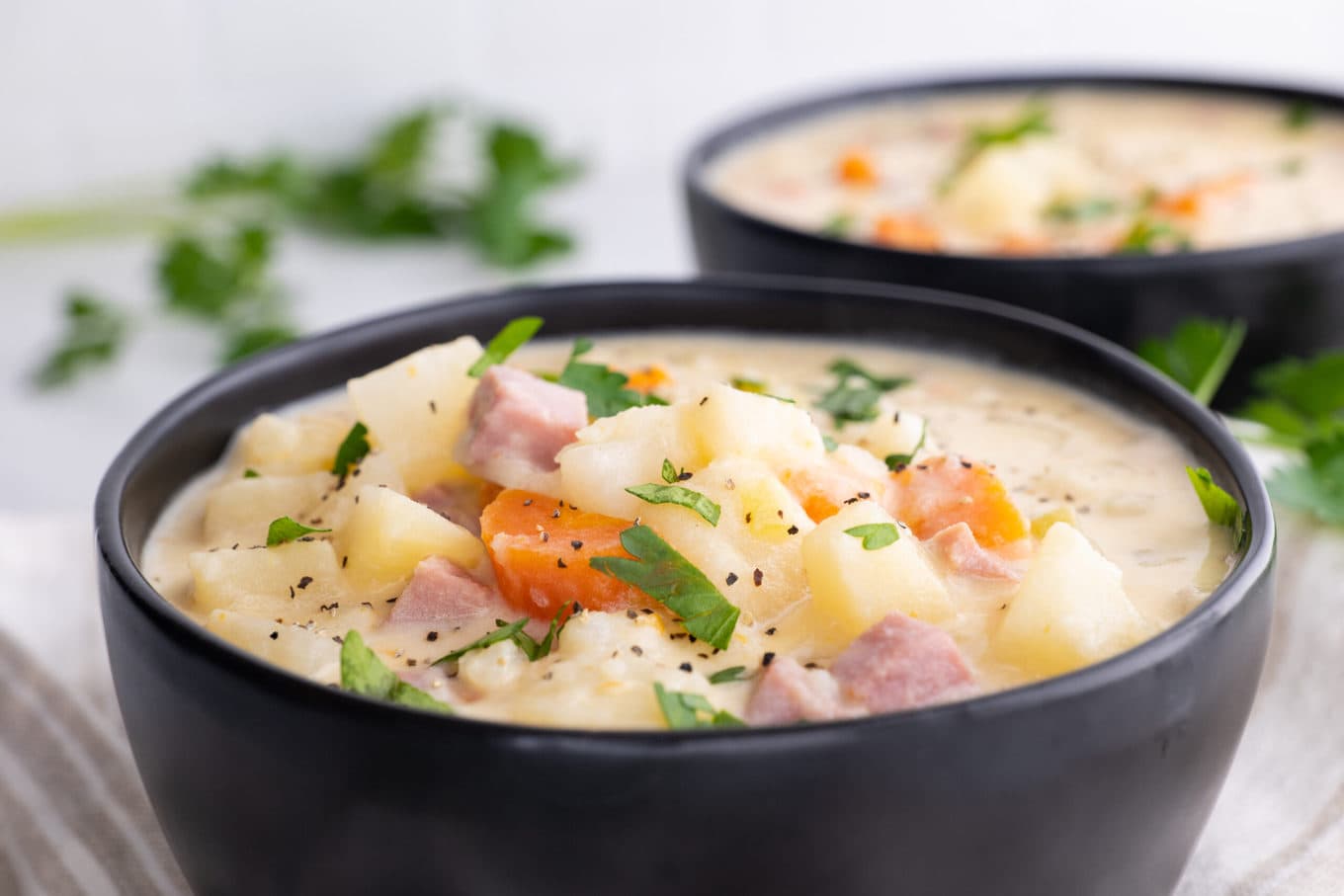 Slow Cooker Ham and Potato Soup in bowls with parsley garnish