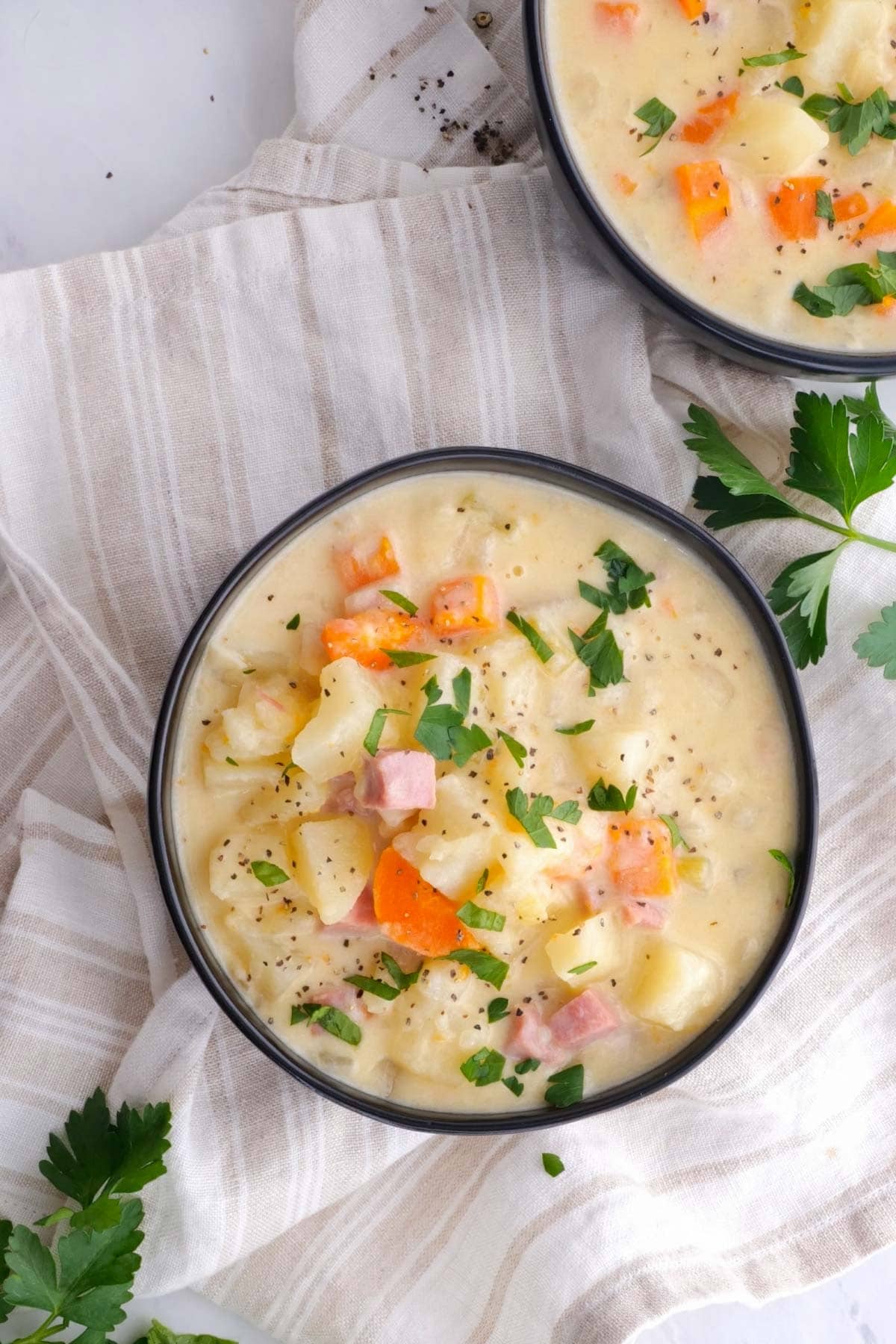 Slow Cooker Ham and Potato Soup in bowls with parsley garnish