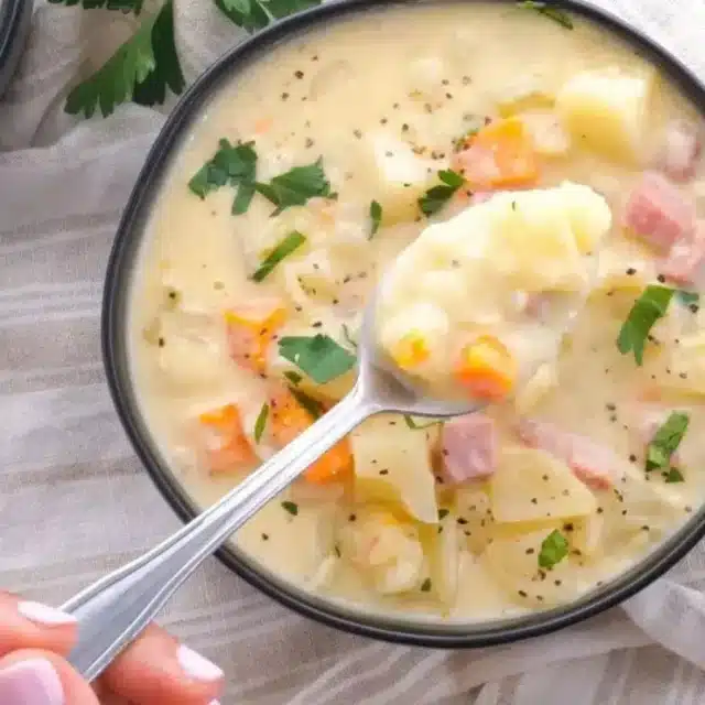 Hand holding spoon with soup in it over bowl of soup