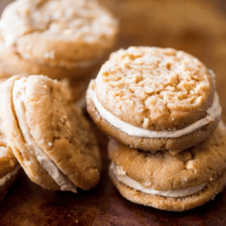 Peanut butter and oatmeal cookies sandwiched together with a fluffy, soft peanut butter buttercream filling sitting on the table.