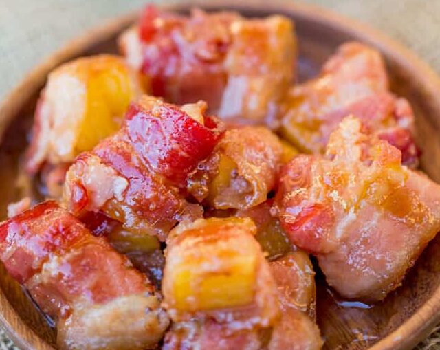 Spicy Sweet Bacon Wrapped Pineapple Bites on wood plate