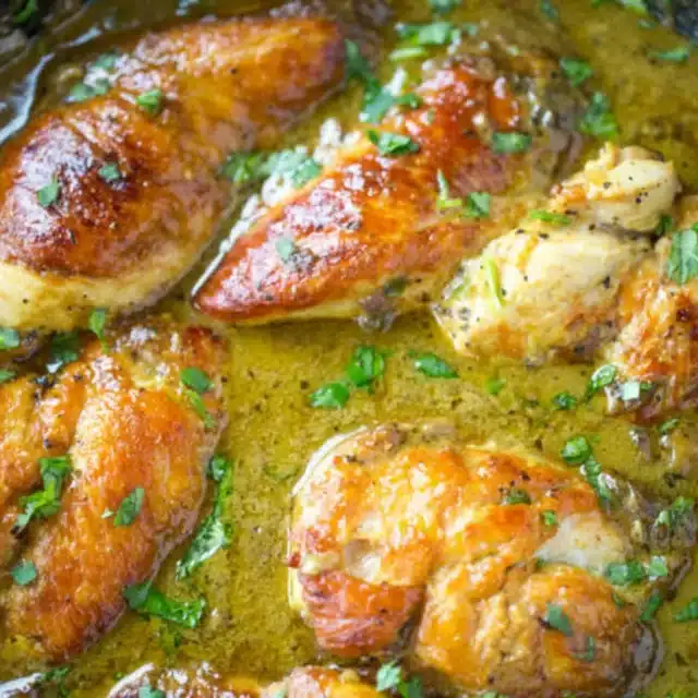 Chicken cooked in pot with juice and garnishment