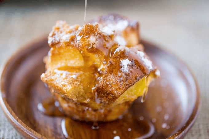Pouring maple syrup poured over French toast bite