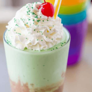 chocolate and mint shake topped with whipped cream, cherry and green sprinkles