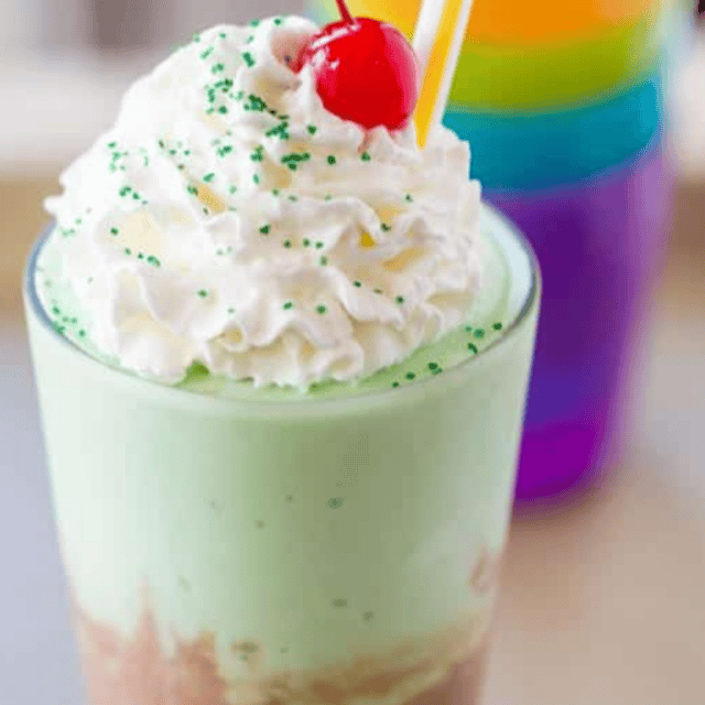 chocolate and mint shake topped with whipped cream, cherry and green sprinkles