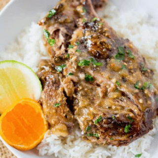 pork on top of rice with lemon and lime on the side