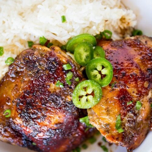 two chicken thighs in bowl with rice and jalapeno slices