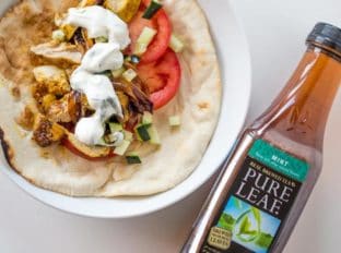 Chicken Shawarma Pita Wraps with Dill Yogurt Sauce are baked on a sheet pan with sweet red onions and wrapped in a pita for the ultimate lunch without the long lines at your favorite lunch restaurant.