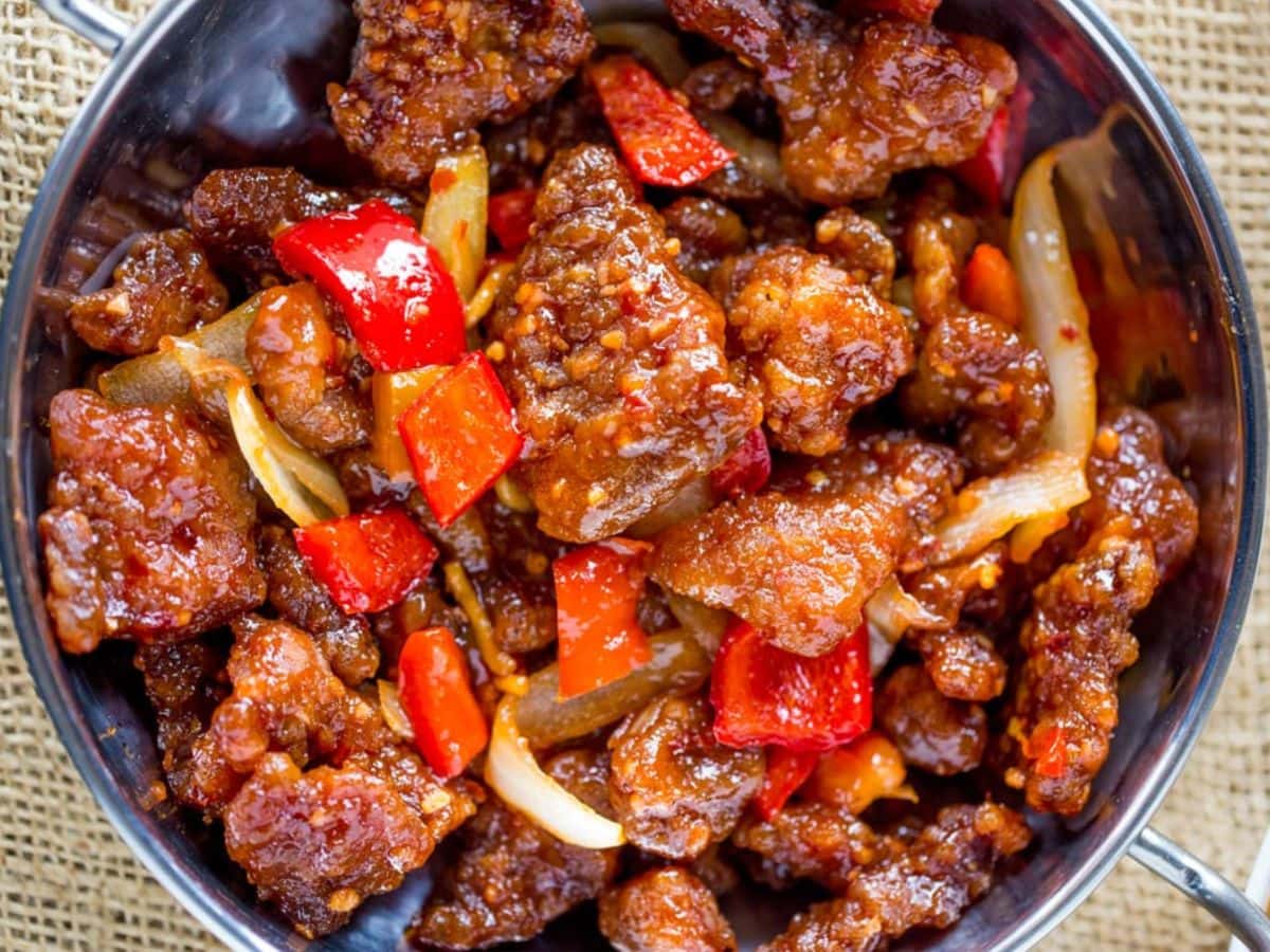 Panda Express Beijing Beef with bell peppers and sliced onions, tossed in the wok with a tangy sweet and spicy sauce. A tasty spot-on copycat! Cooked beef and veggies in sauce in pan.