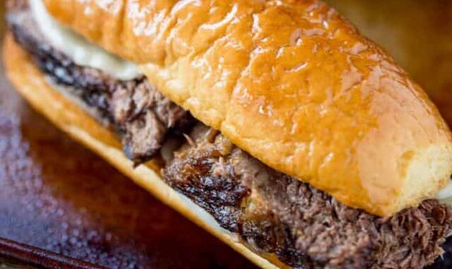 French dips on wooden board with au jus