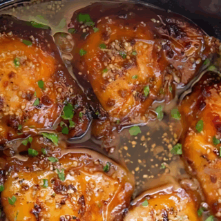 cooked chicken in pot with garlic, sauces, and garnish