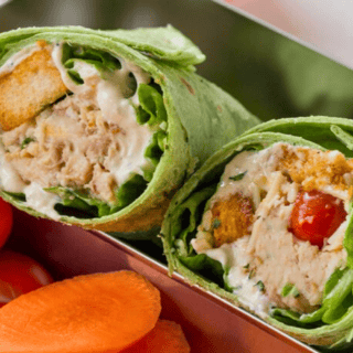 cooked poultry with croutons, tomatoes, cheese, and greek yogurt wrapped in spinach tortilla