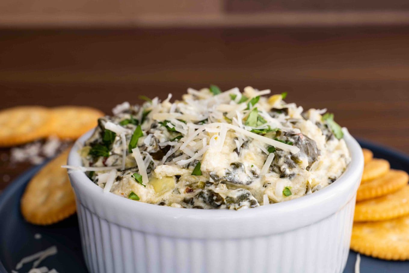 Slow Cooker Spinach Artichoke Dip in bowl on serving plate with crackers