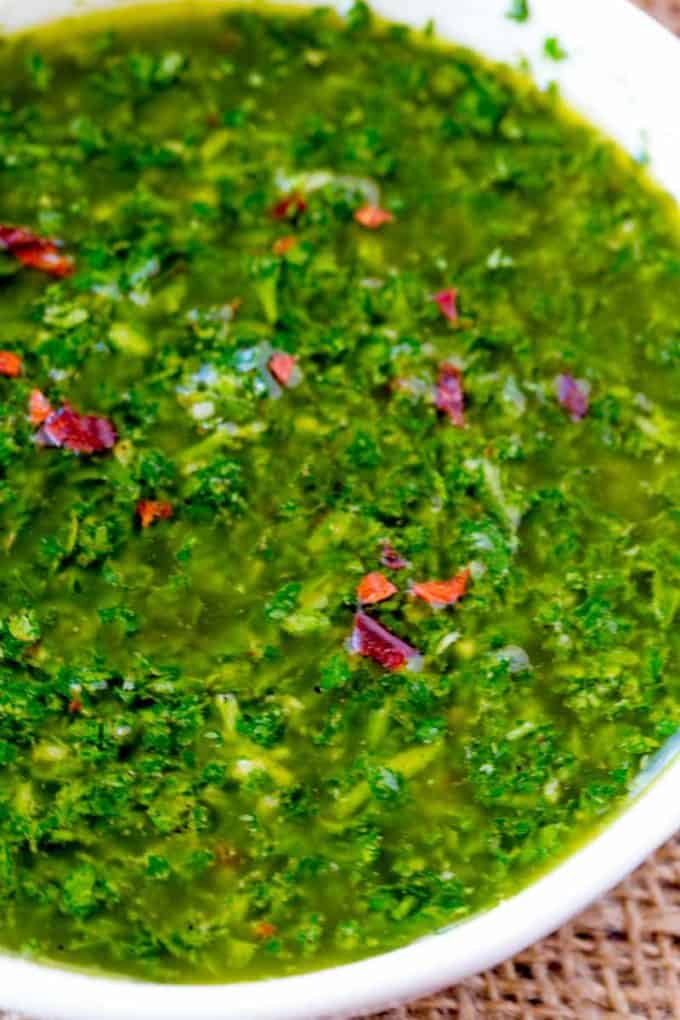 Chimichurri sauce in bowl with red chili flakes