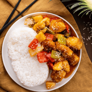 chicken and veggies in sauce with rice on white plate
