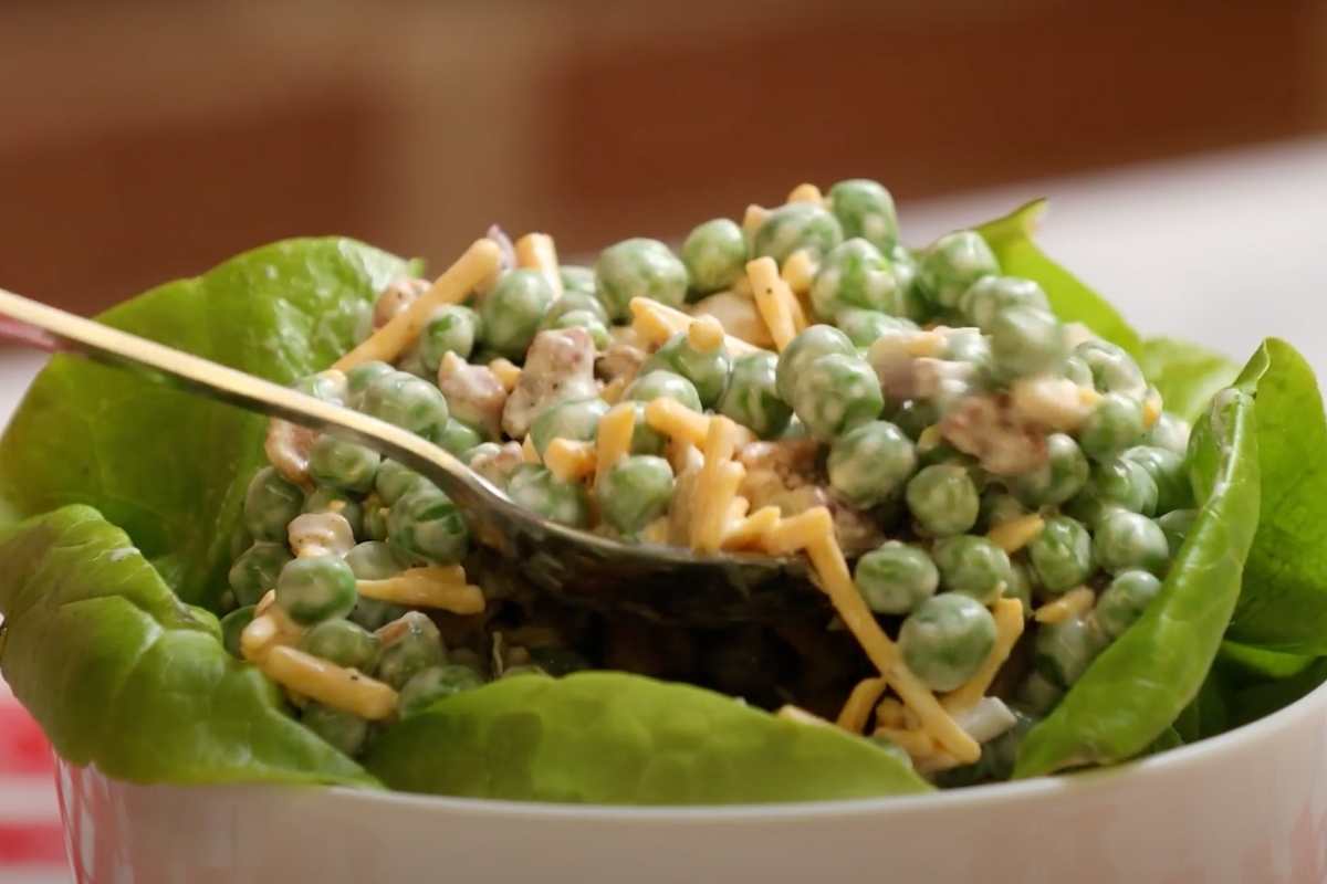 Creamy Bacon Pea Salad on bed of lettuce with spoon