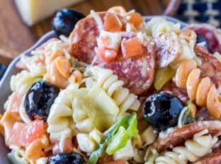 Italian Antipasto Pasta Salad is delicious and easy with creamy Italian dressing, cheese, salami, olives, tomatoes, bell peppers and pasta that's the perfect addition to your summer menus!