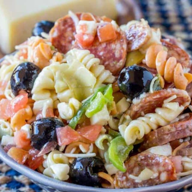 Bowl of combined and dressed pasta salad on blue check cloth