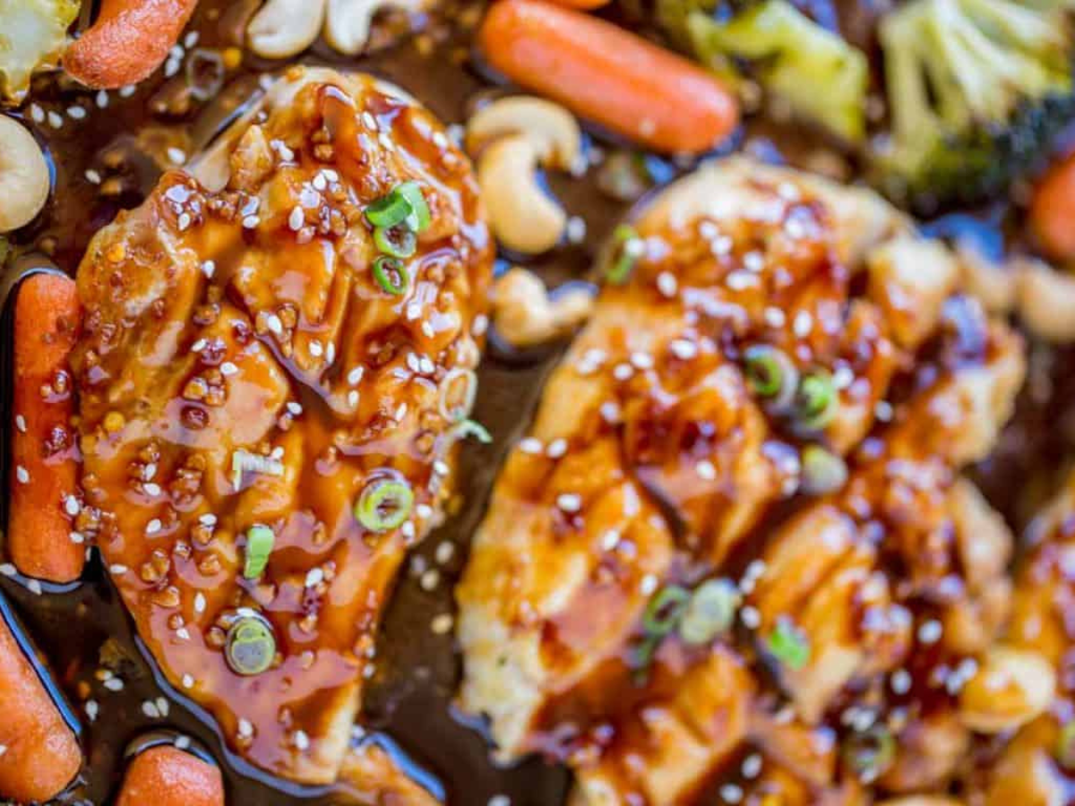 Zoomed in picture of chicken carrots and broccoli on a sheet pan