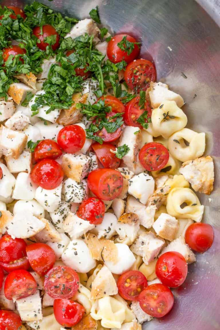 Unmixed pasta salad ingredients in a metal bowl