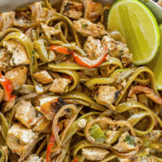 pasta and chicken in a bowl with limes