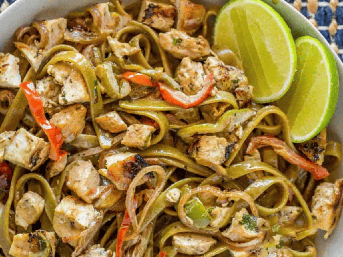 pasta and chicken in a bowl with limes