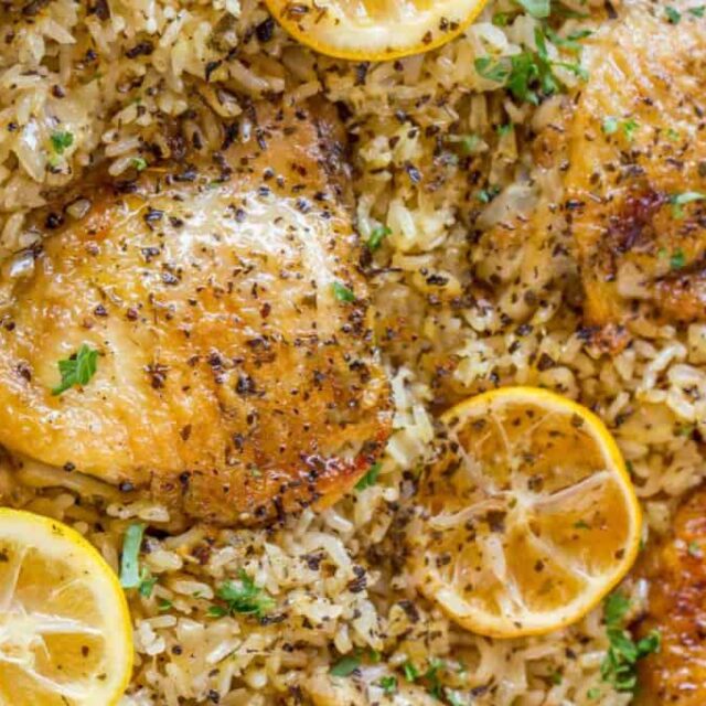 cast iron skillet with chicken, rice, and lemon
