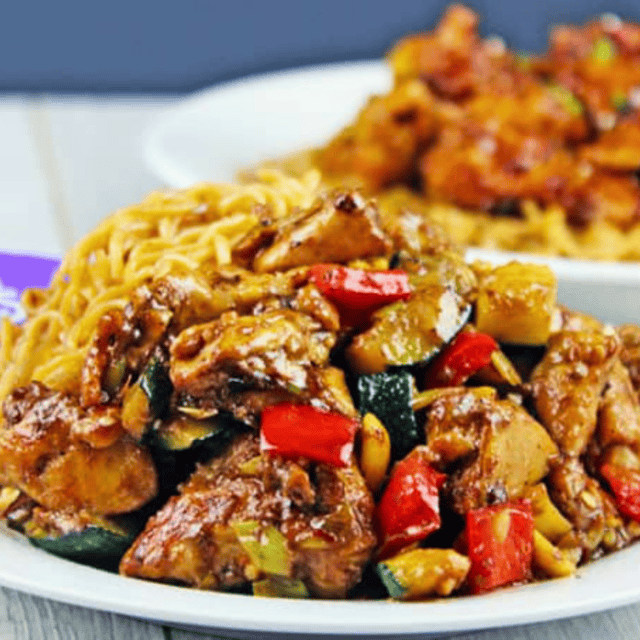 Plated kung pao chicken and veggies with chow mein