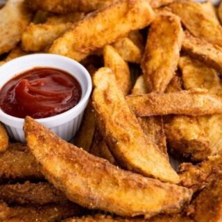 potatoes on a sheet pan with a dish of ketchup.