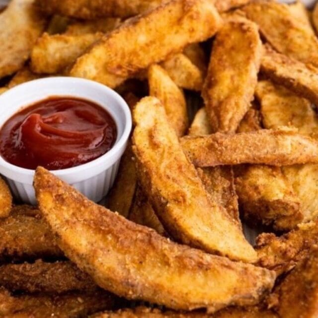 potatoes on a sheet pan with a dish of ketchup.