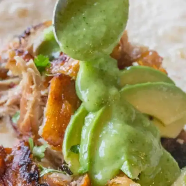 avocado sauce on top of chicken on a tortilla