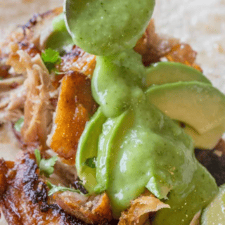 Spooning prepared green salsa over charred chicken.