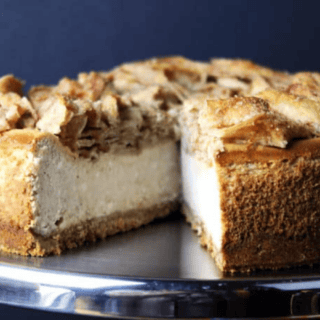 whole cheesecake on a platter with a slice missing