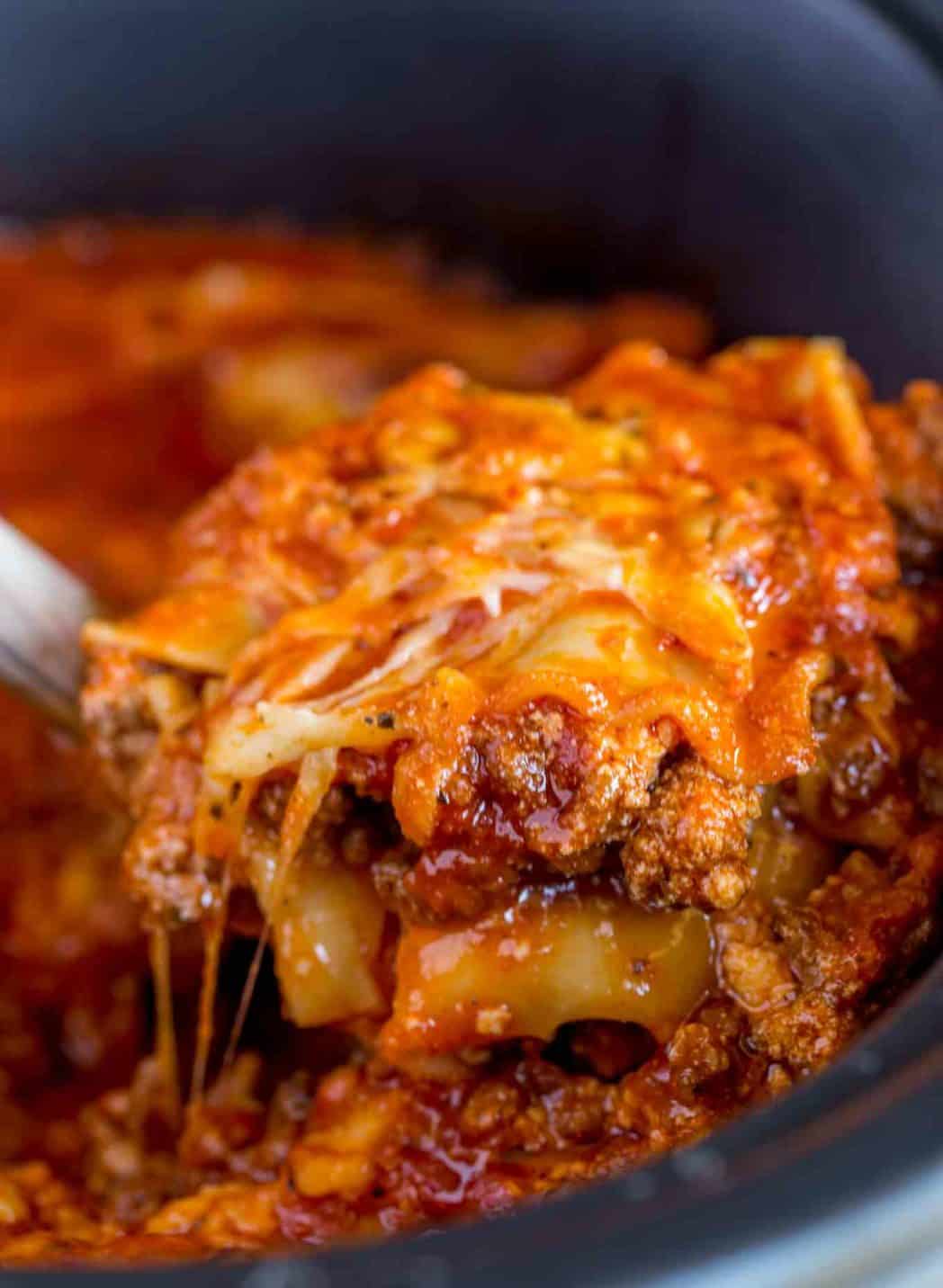 Lifting slice of lasagna out of crock pot.
