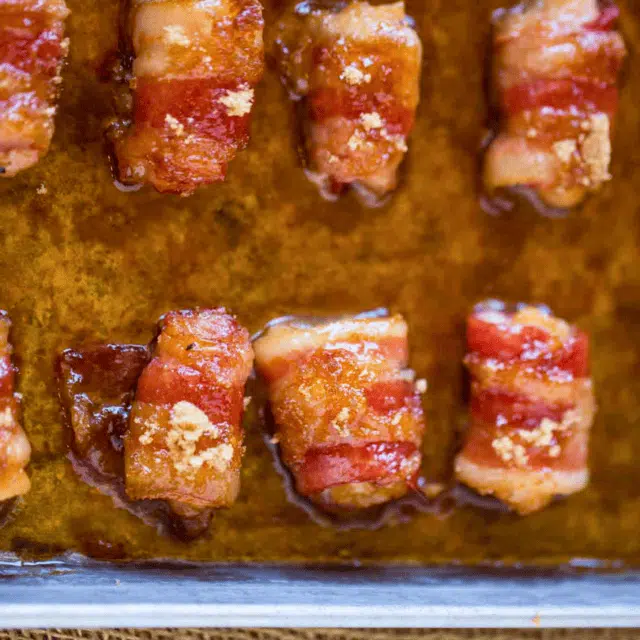 caramelized pork strip wrapped around a piece of poultry side by side on a baking sheet