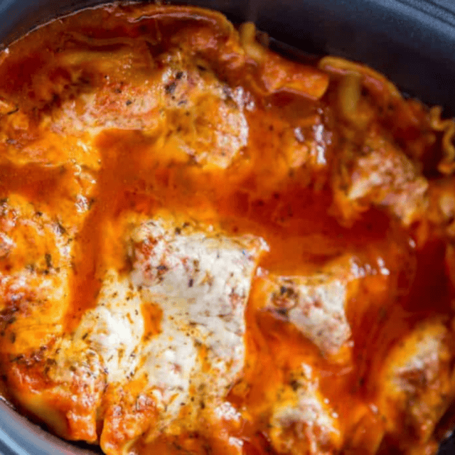cooked pasta dish with layers of meat, sauce and cheese in a crockpot