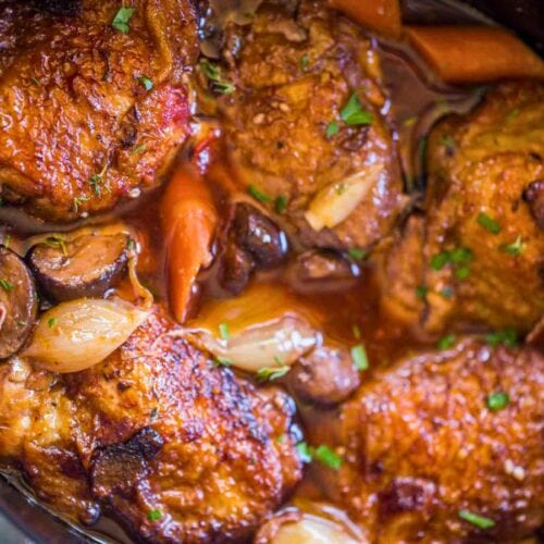 chicken thighs cooked in sauce with veggies in slow cooker.
