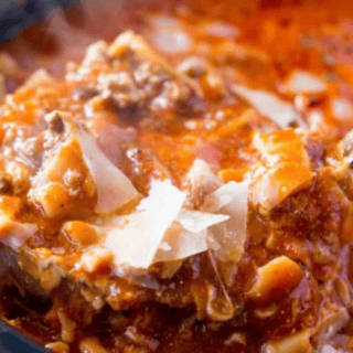 close up of ladle of hearty soup topped with Parmesan