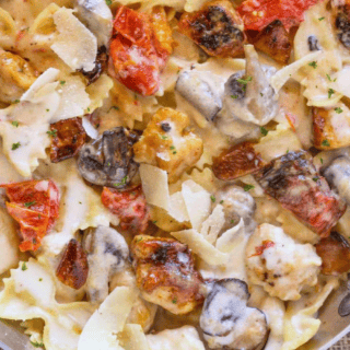 cooked pasta and chicken with tomatoes in garlic sauce in pan