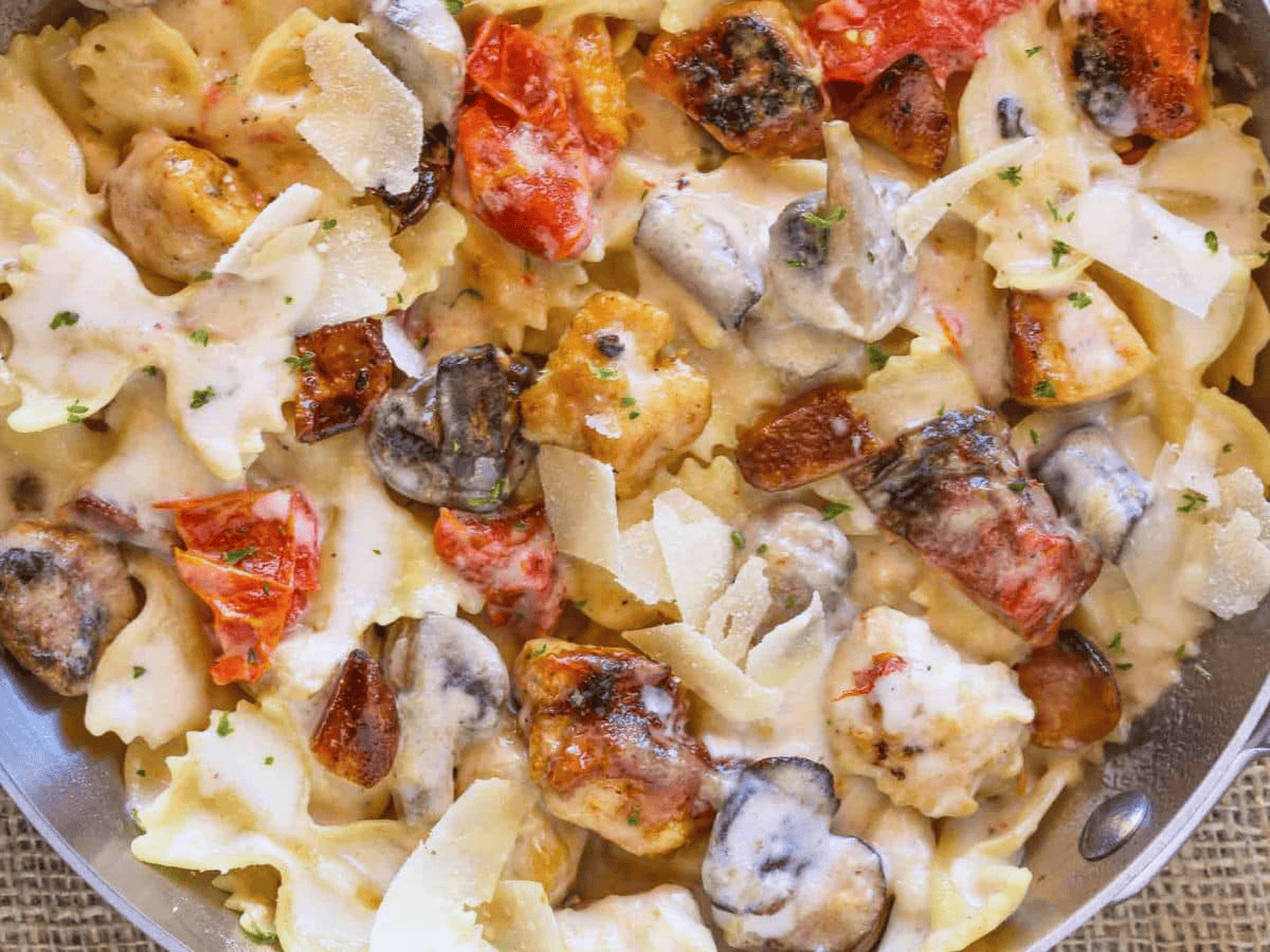 cooked pasta and chicken with tomatoes in garlic sauce in pan