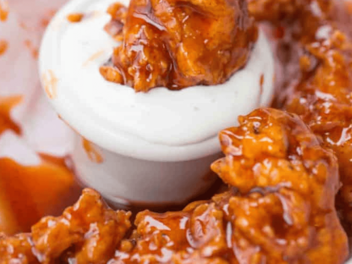 Chicken being dipped into sauce
