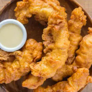 chicken tenders on a plate with a small bowl of sauce