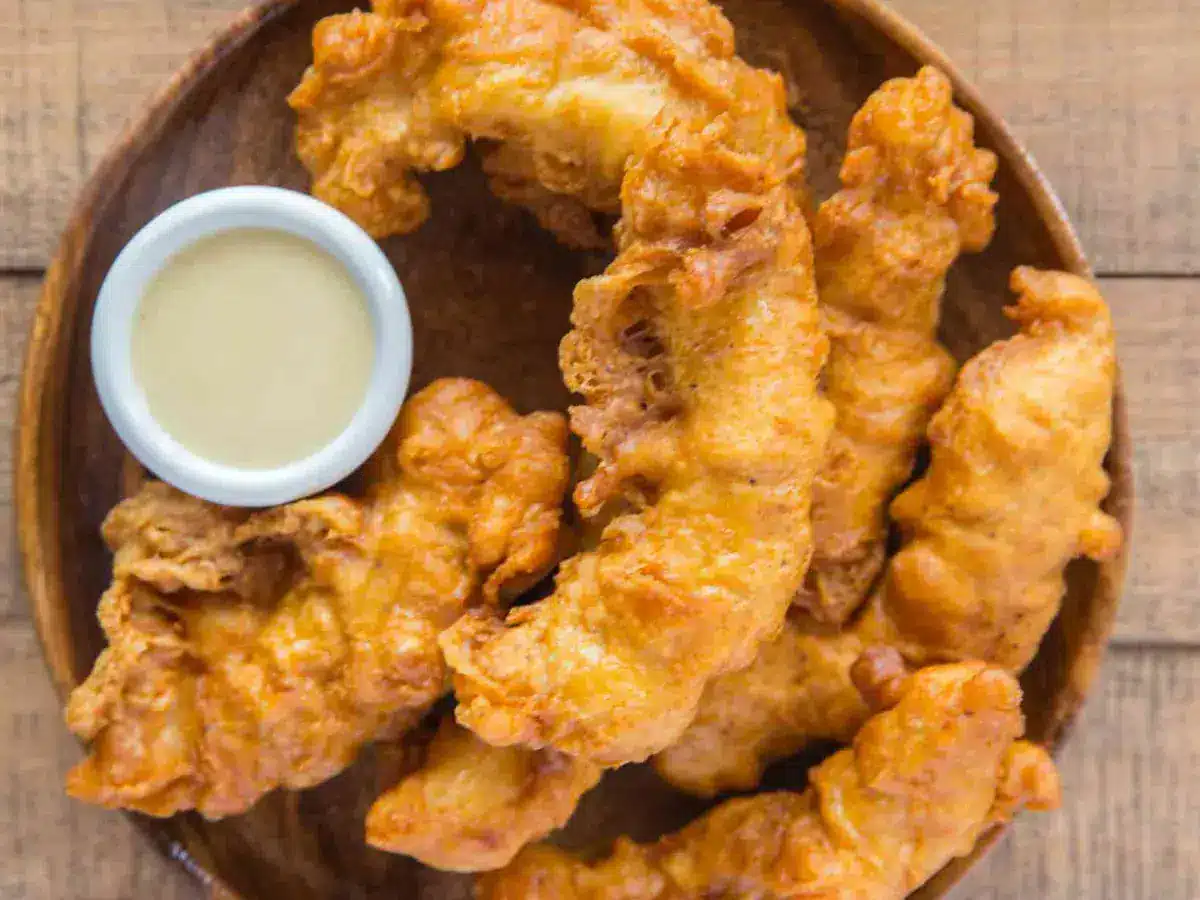 chicken tenders on a plate with a small bowl of sauce